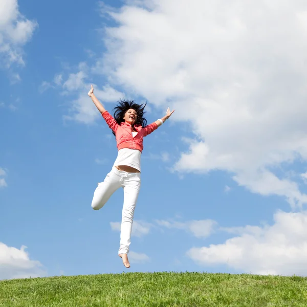 漂亮的年轻女人在绿草地上跳跃 — 图库照片