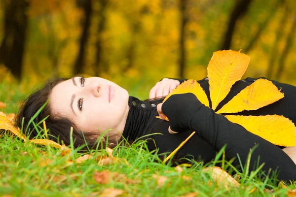 Nuori kaunis nainen syksyllä lehtiä — kuvapankkivalokuva