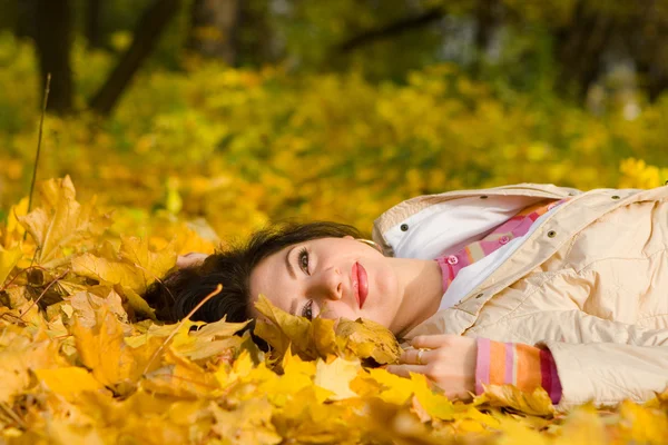 stock image Young pretty women rest on the autumn leaf