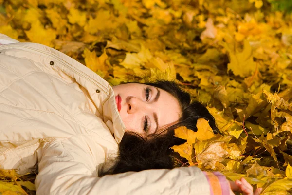 Genç kadın dinlenme sonbahar yaprak üzerinde oldukça — Stok fotoğraf