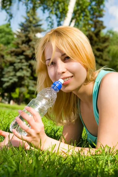 Ładna kobieta wody pitnej na polanie lato — Zdjęcie stockowe