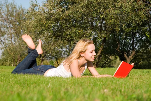 Giovane bionda legge libro nel parco — Foto Stock