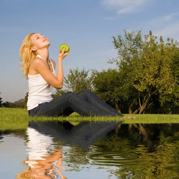 Jolie femme mangeant de la pomme verte sur la clairière d'été — Photo