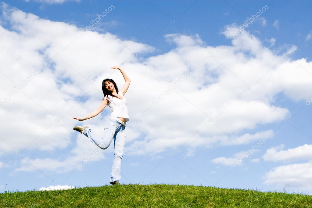Pretty young woman dance on green grass