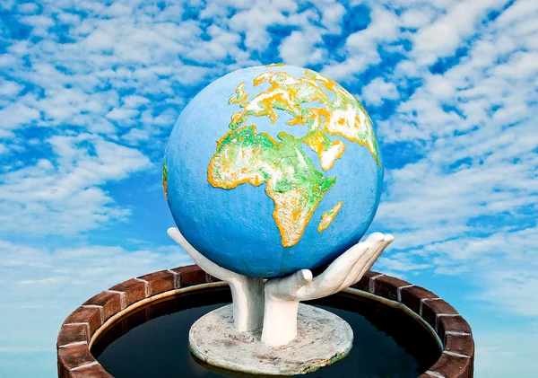 The Sculpture of world in hand on blue sky background — Stock Photo, Image
