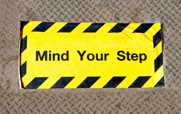 El signo de precaución mente el paso en el piso de acero —  Fotos de Stock