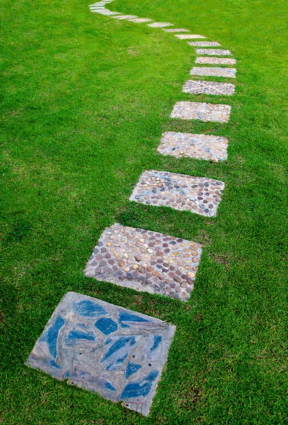 O bloco de pedra caminho de caminhada no parque com fundo de grama verde — Fotografia de Stock