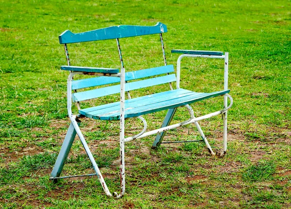 Старая скамейка на зеленом фоне травы — стоковое фото