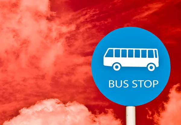 La señal de parada de autobús en poste aislado en el fondo del cielo rojo —  Fotos de Stock