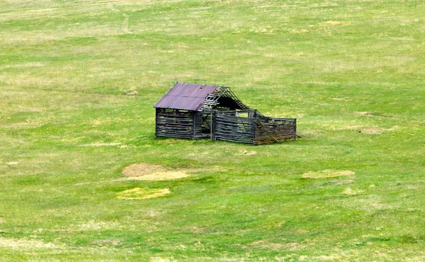 Antigua cabaña de troncos en un prado de montaña — Foto de Stock