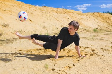 Kumsalda futbol oynayan genç adam