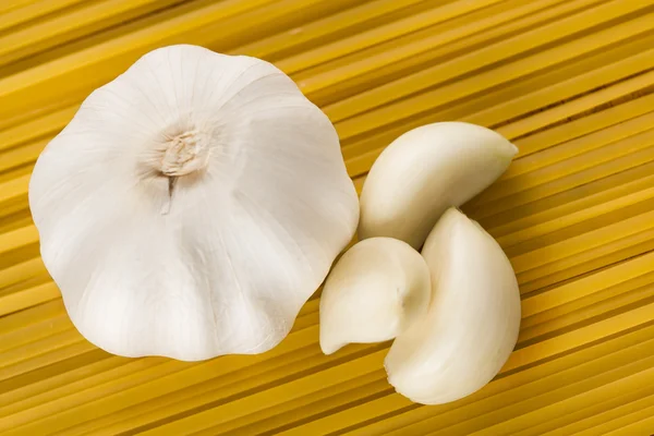 Fresh garlic head and cloves on pasta table — Stock Photo, Image