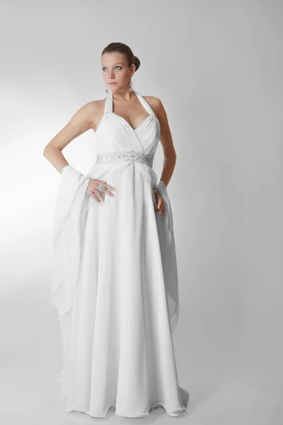 Belle femme portant une robe de mariée luxueuse sur fond de studio gris — Photo