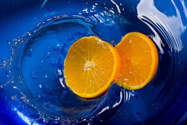 Sinaasappelen op water blauwe achtergrond — Stockfoto