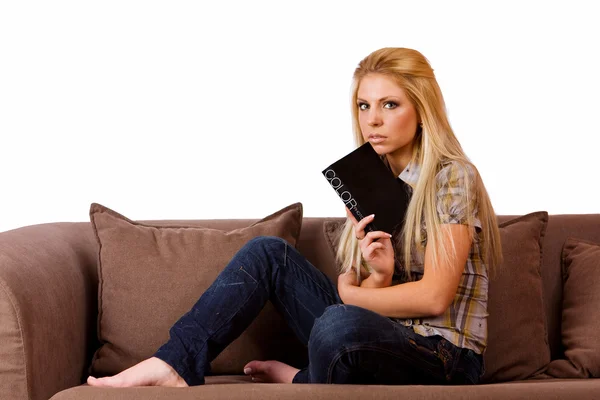 Bonito jovem loira lendo um livro preto no sofá — Fotografia de Stock