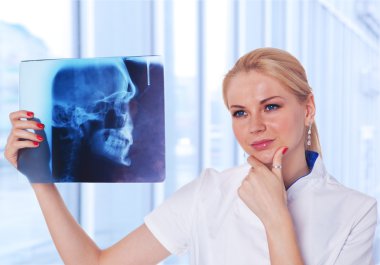 Portrait of attractive woman doctor looking at X-ray results of clipart