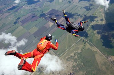 Two skydivers flying above the clouds clipart