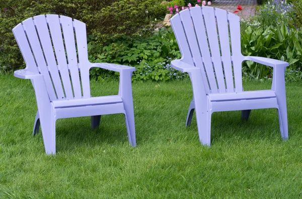 Two purple chairs on a green lawn