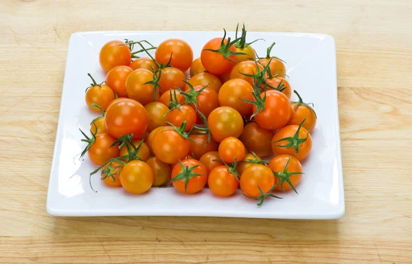 Tomates cereja laranja exibidos na placa branca — Fotografia de Stock