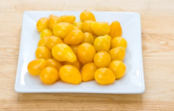 Gele peer cherry tomaten weergegeven op wit bord — Stockfoto