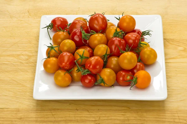 Red and yellow cherry tomatoes on white plate — Stock Photo, Image