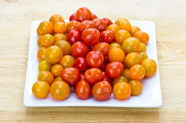 Red yellow and orange cherry tomatoes on white plate — Stock Photo, Image