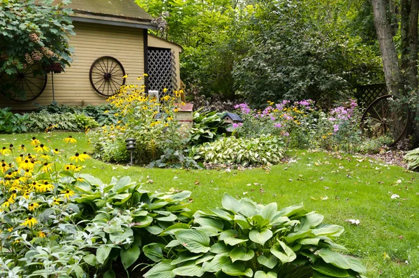 Zahrada s žlutým kůlny a trávník — Stock fotografie