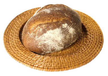 Fresh baked loaf of sourdough rye bread on wicker tray clipart