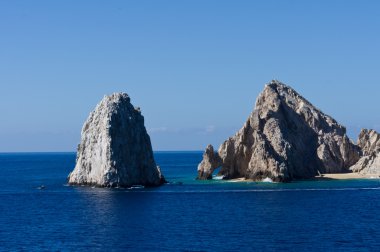 Rock formations including El Arco rise from the ocean clipart