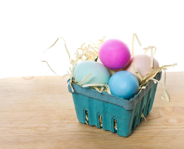 Küçük yeşil sepet renkli yumurta ve saman — Stok fotoğraf