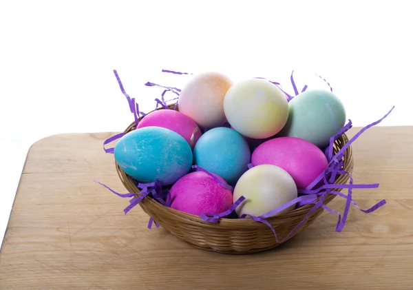 Wiklinowy koszyk kolorowych jaj i słomy — Zdjęcie stockowe