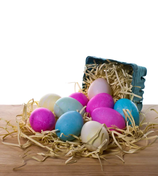 Small basket with colorful eggs spilling onto table — Stock Photo, Image