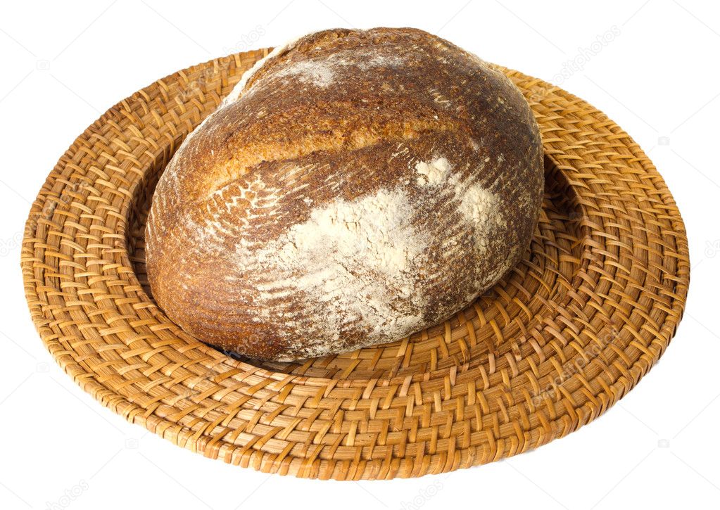 Fresh baked loaf of sourdough rye bread on wicker tray
