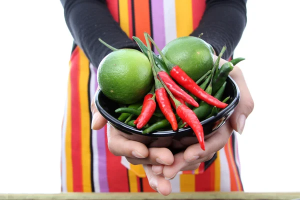 stock image Women in colorful apron holding fresh red, green chili and lime