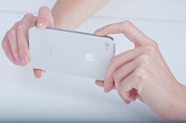 Female hands with a manicure keeps white iphone 4 on a white clipart