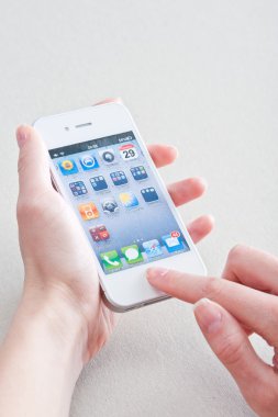 Female hands with a manicure keeps white iphone 4 on a white clipart