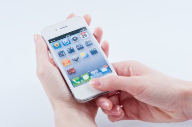 Female hands with a manicure keeps white iphone 4 on a white clipart