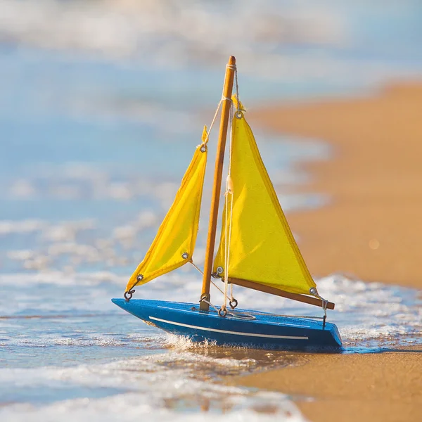 stock image The little toy boat stands on sandy beach