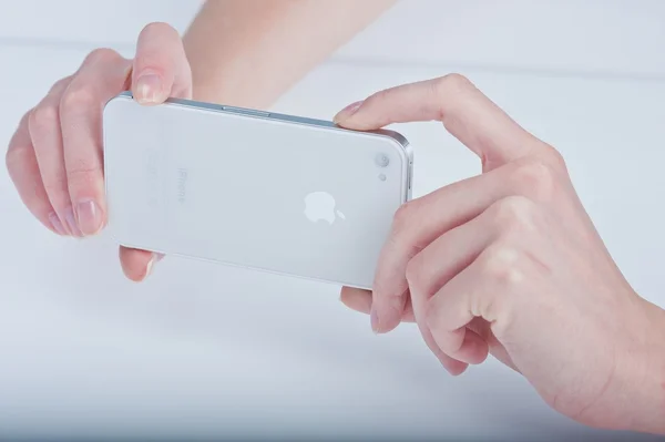Las manos femeninas con la manicura mantienen blanco iphone 4 sobre blanco — Foto de Stock
