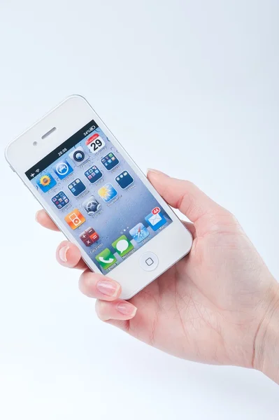Женские руки с маникюром держит белый iphone 4 на белом — стоковое фото