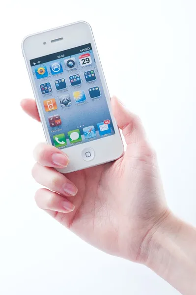 Dedos de las mujeres con una manicura mantiene el iphone blanco 4 4S en un blanco — Foto de Stock