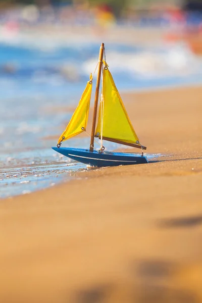 stock image The little toy boat stands on sandy beach