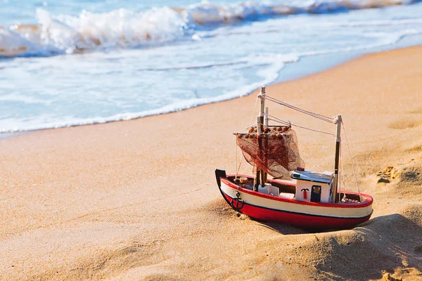 El pequeño barco de juguete se encuentra en la playa de arena — Foto de Stock