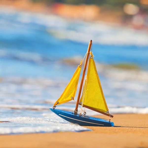 stock image The little toy boat stands on sandy beach