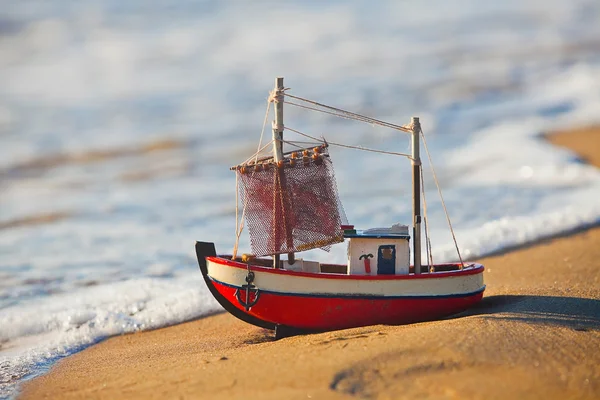 Liten leksak båten står på sandstranden — Stockfoto