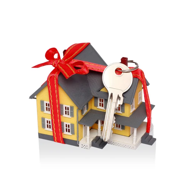 Dar domu miniaturze z czerwoną wstążką i klucz na białym tle - wł — Zdjęcie stockowe