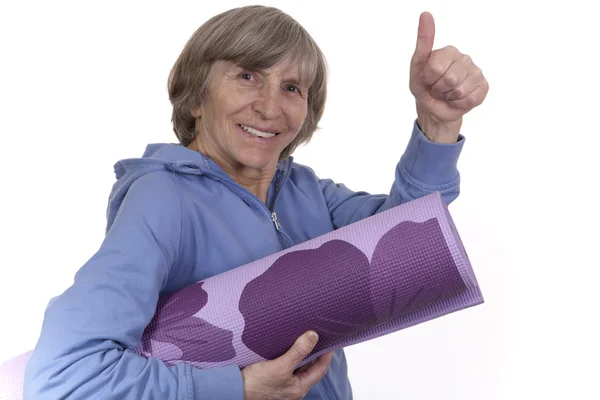 stock image Retired woman holding a yoga mat while showing thumb up