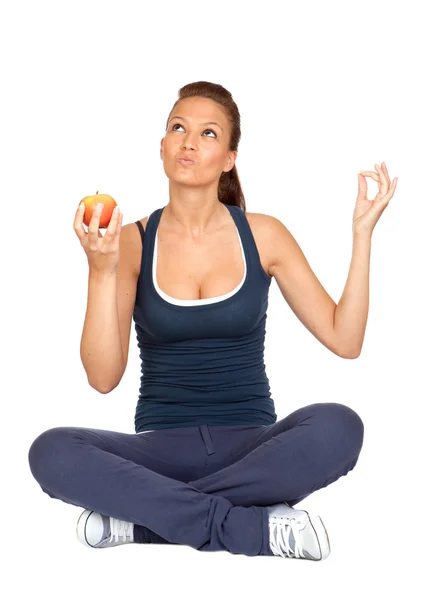 Девушка-гимнастка с яблоком, сидящая с перекрещенными ногами — стоковое фото