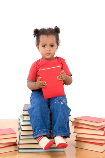 Bambino che legge seduto su un mucchio di libri — Foto Stock