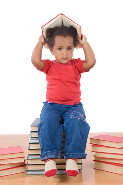 Barnet sitter på en hög med böcker — Stockfoto